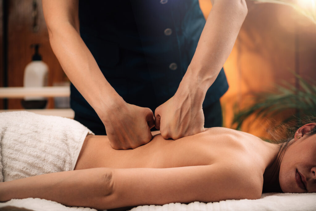 Therapeutic massage therapist performing a Tulsa deep tissue massage using focused pressure along the back as part of a medical massage of Tulsa treatment.