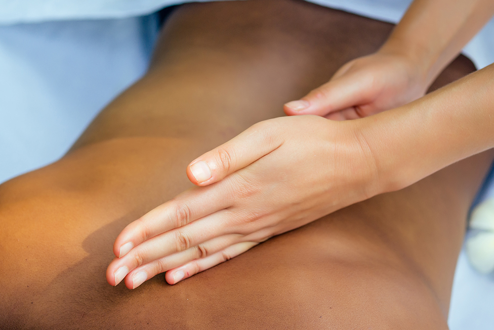 Hands performing a therapeutic massage along the back during a Tulsa deep tissue massage session at a medical massage of Tulsa clinic.