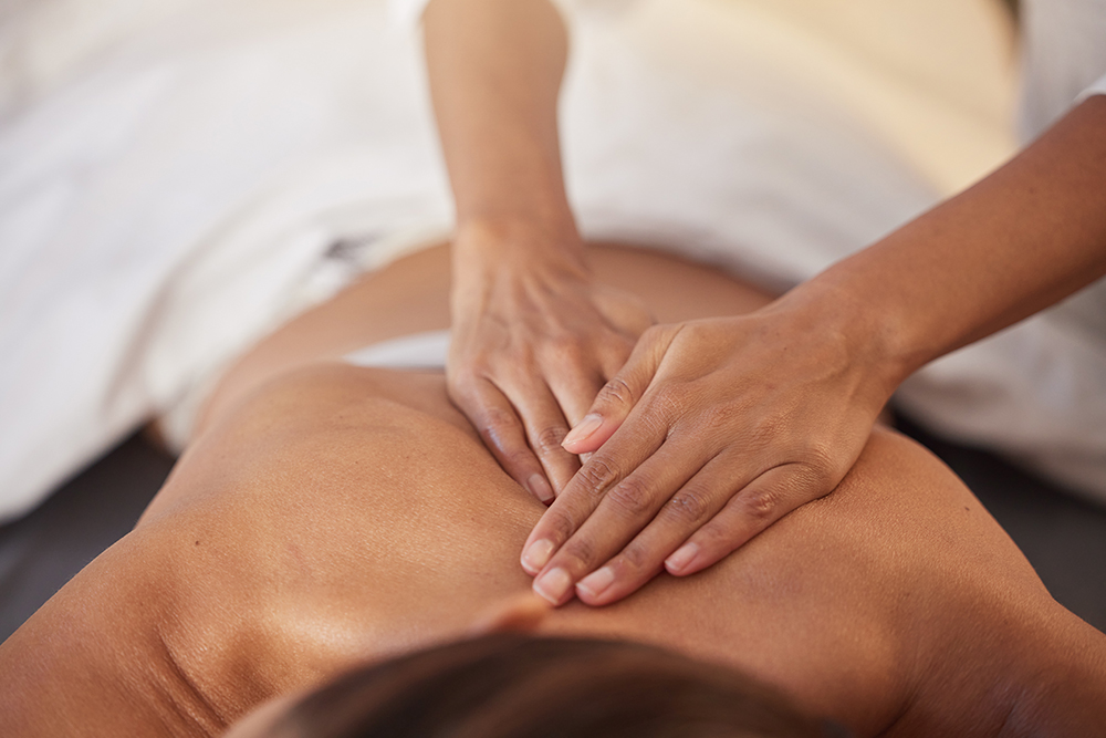 Therapist using palm pressure along the back during a Tulsa deep tissue massage session at a medical massage of Tulsa clinic.